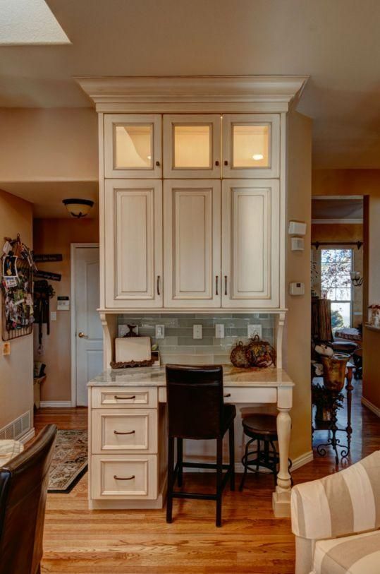 Built-in white desk nook with drawers, chair, and overhead cabinets in a cozy home interior