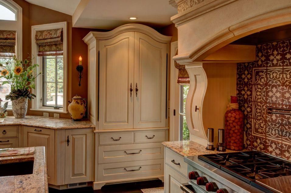 Warm kitchen with cream cabinets, tiled backsplash, window seat, and a gas range beside a decorative hood.
