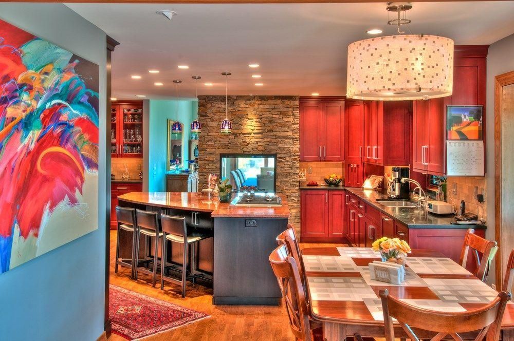 Bright modern kitchen and dining area with red cabinets, island seating, and colorful wall art
