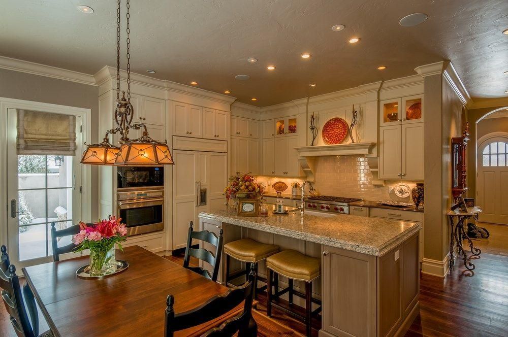 Bright kitchen with island, pendant lights, cream cabinets, and a small flower arrangement by the window