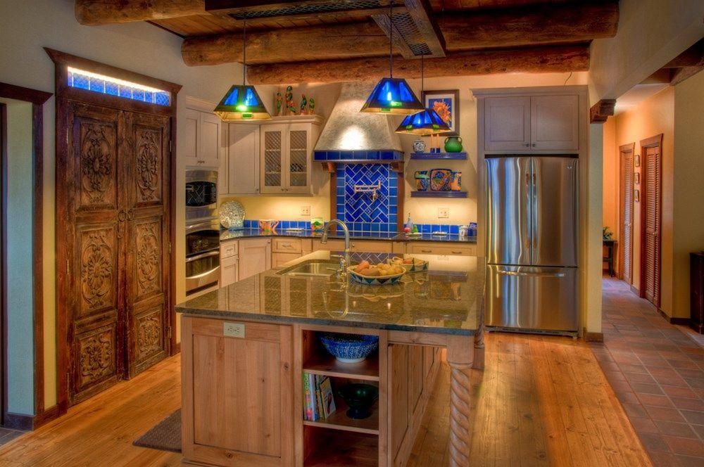 Warm rustic kitchen with wood cabinets, granite island, blue tile backsplash, and stainless steel refrigerator