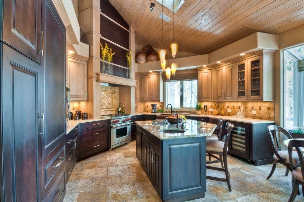 Modern kitchen with dark wood cabinets, central island, pendant lights, and tiled floor