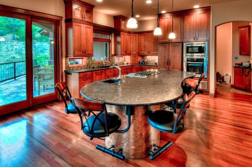 Modern kitchen with cherry cabinets, granite island, barstools, pendant lights, and hardwood floors
