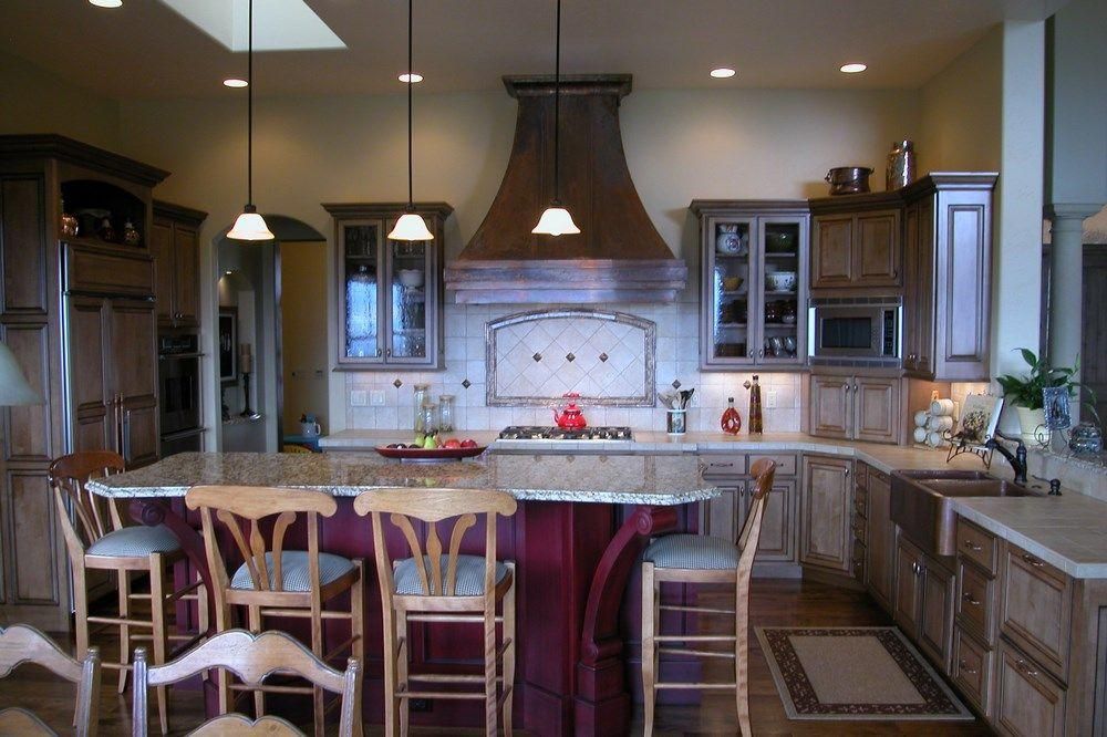 Modern kitchen with a large island, wooden bar stools, pendant lights, and stainless steel appliances.