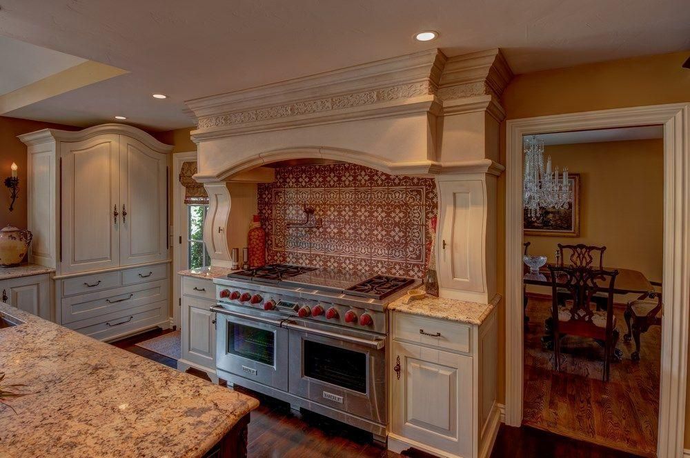 Elegant kitchen with cream cabinets, tiled backsplash, and a large stainless steel range