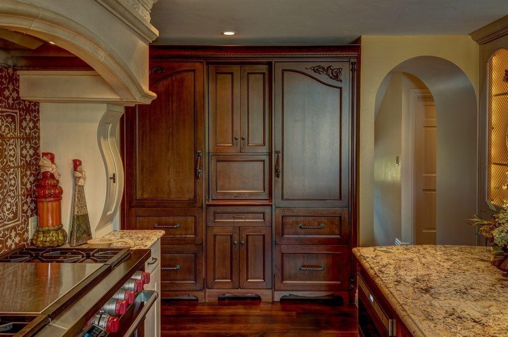 Warm-toned kitchen with granite counters, wood cabinets, and a stone archway.