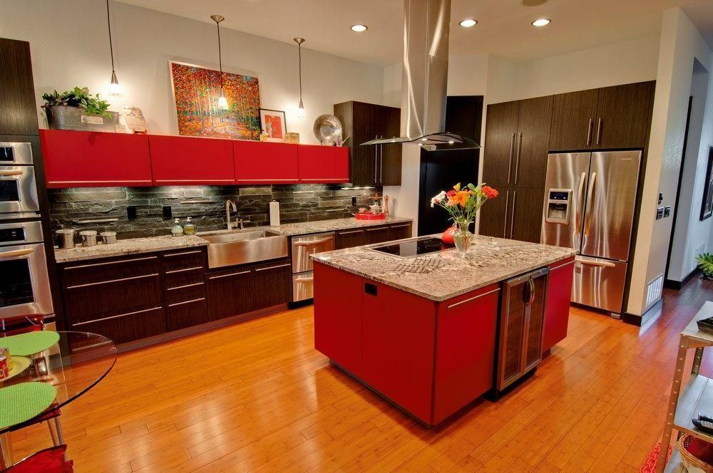 Modern kitchen with red island, dark cabinets, stainless steel appliances, and wood floors