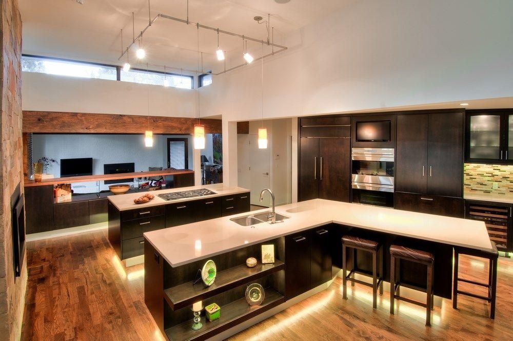 Modern kitchen with dark wood cabinets, island, bar stools, and warm hardwood floors