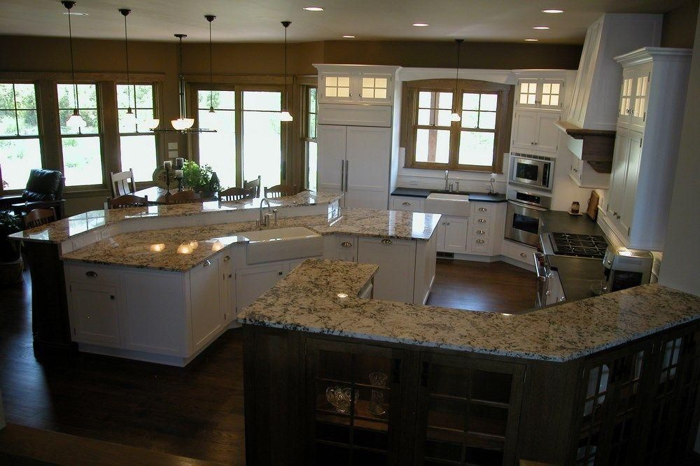 Spacious modern kitchen with granite countertops, white cabinets, and a large island near bright windows.