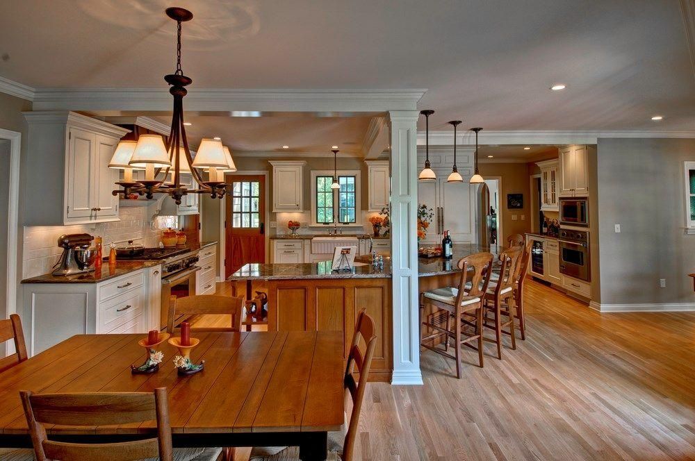 Spacious open kitchen and dining area with wood floors, white cabinets, and a wooden table