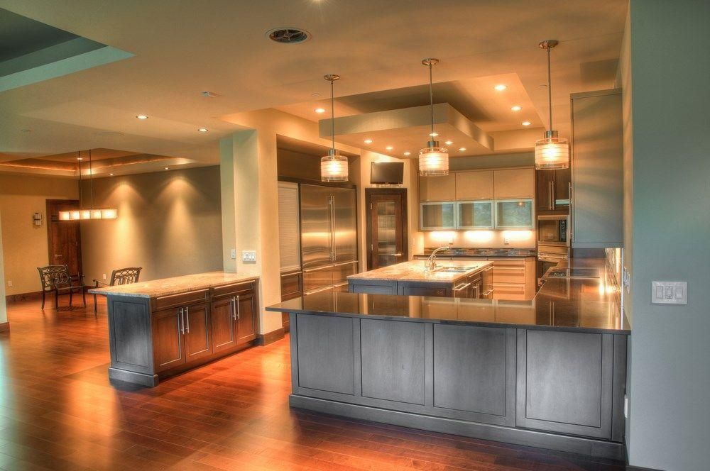 Spacious modern kitchen with dark wood cabinets, stainless appliances, island, and warm pendant lighting.