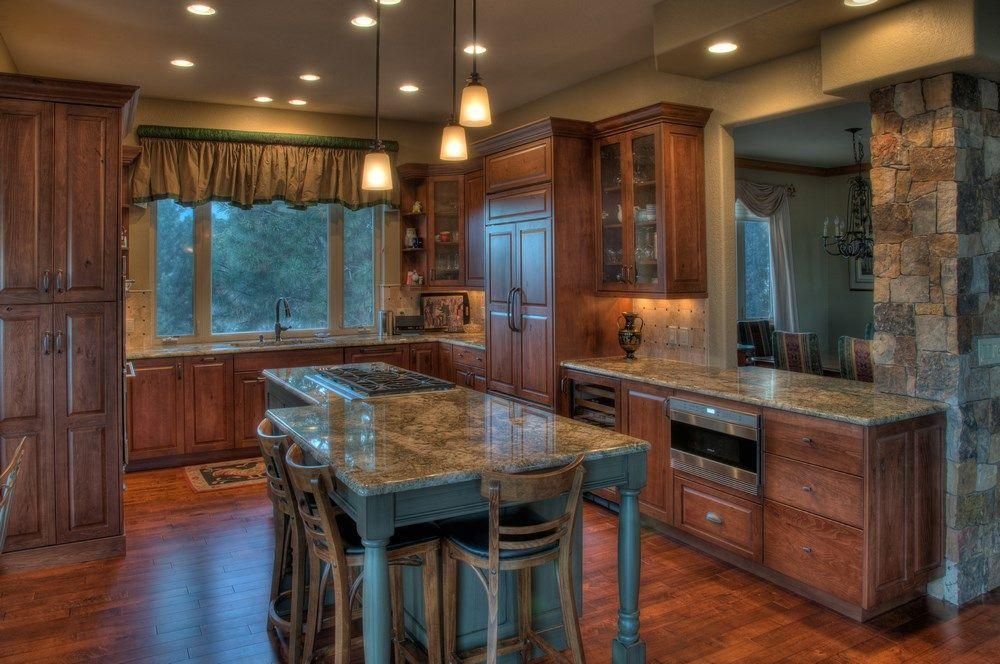 Warm modern kitchen with wood cabinets, granite island, and pendant lights