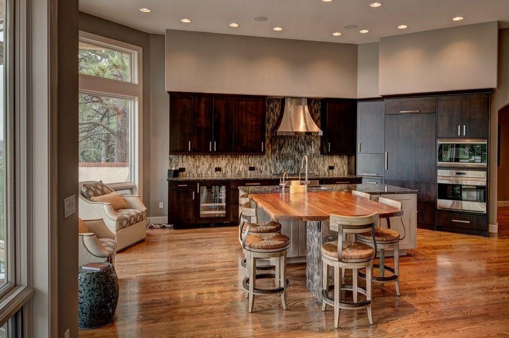 Modern kitchen with dark wood cabinets, stainless hood, island seating, and hardwood floors