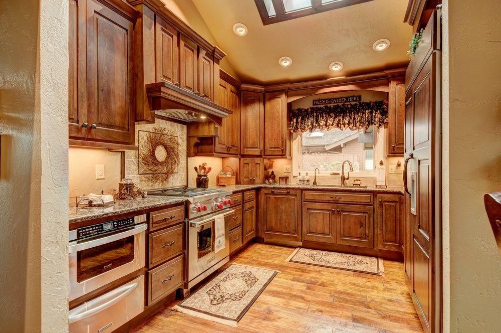 Warm wood kitchen with stainless-steel appliances, granite counters, and tiled backsplash.