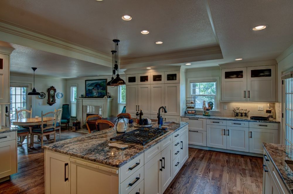 Bright modern kitchen with white cabinets, granite island, wood floors, and pendant lighting