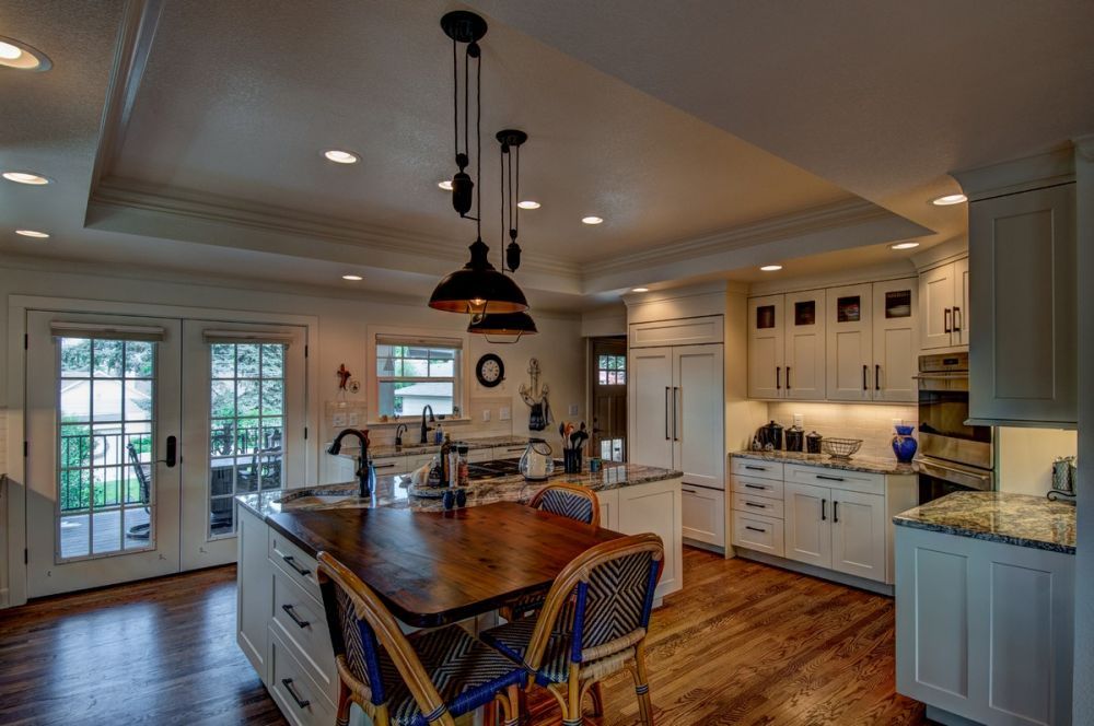 Bright modern kitchen with island, white cabinets, granite countertops, and hardwood floors