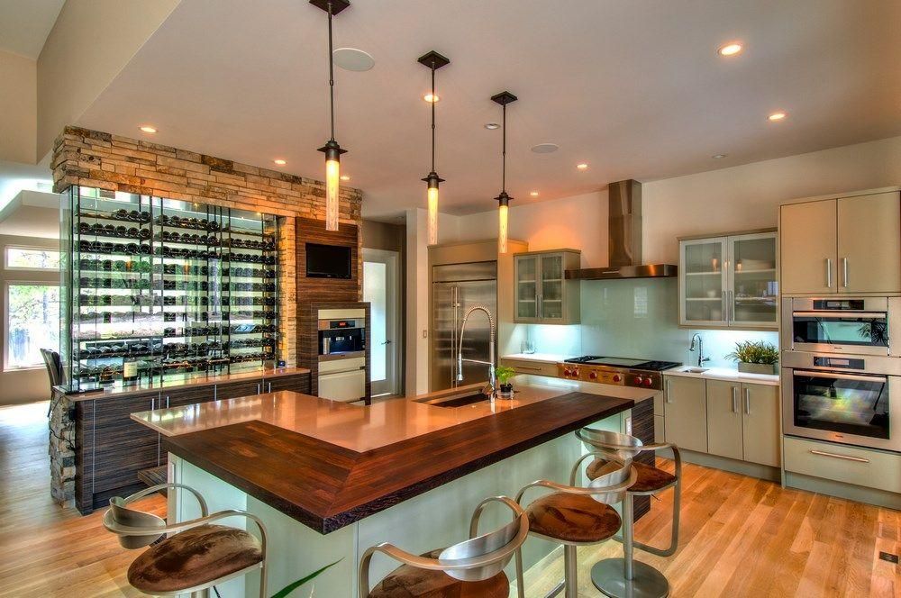 Modern kitchen with large island, pendant lights, wood floors, and stainless steel appliances