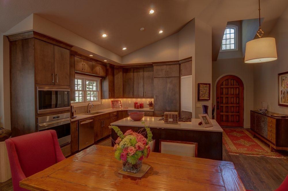 Spacious modern kitchen with wood cabinets, island, dining table, and warm recessed lighting