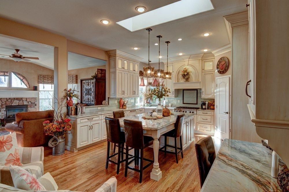Bright kitchen with island, white cabinets, wood floors, and pendant lights in a cozy open-concept home