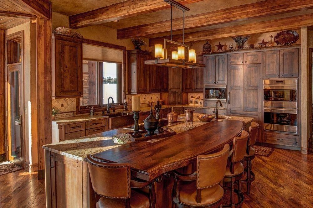 Warm rustic kitchen with wooden island, cabinets, stainless appliances, and pendant lights