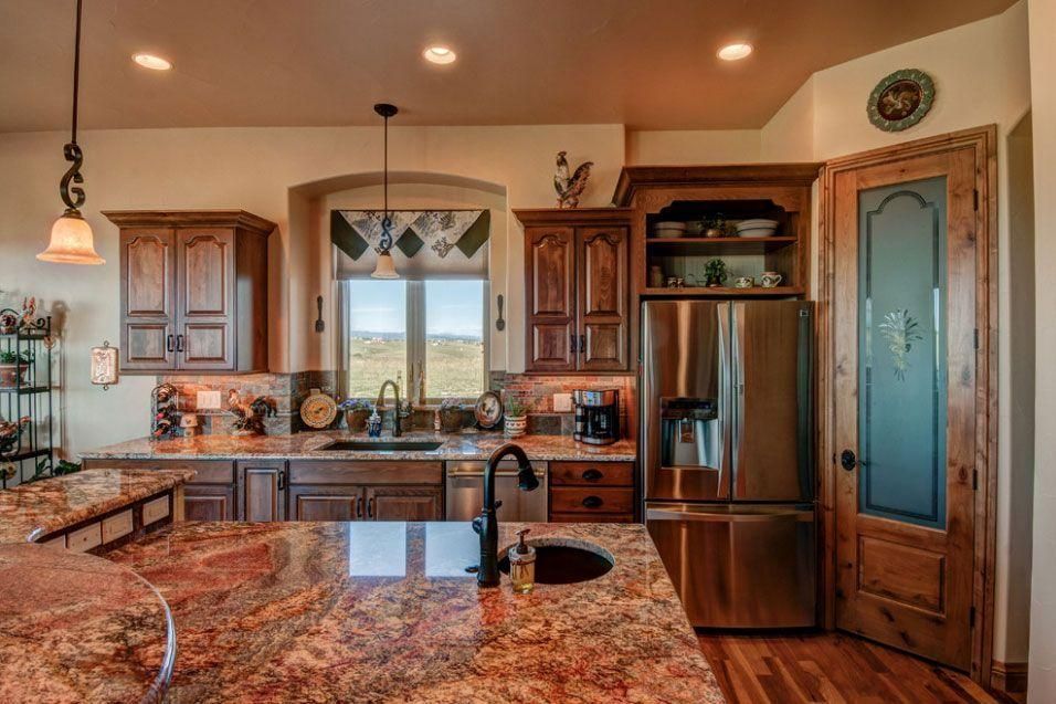 Modern kitchen with granite island, dark wood cabinets, stainless fridge, and glass pantry door