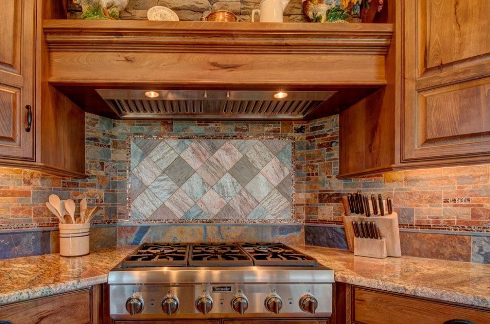 Warm kitchen with stainless range, granite countertops, wood cabinets, and mosaic tile backsplash