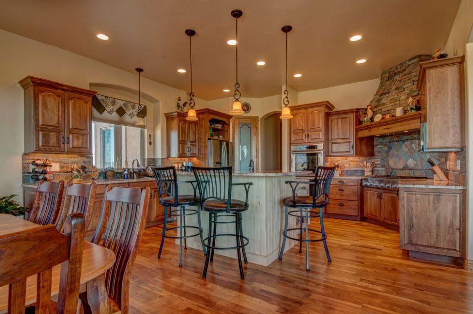 Spacious wooden kitchen with island, bar stools, pendant lights, and tiled backsplash