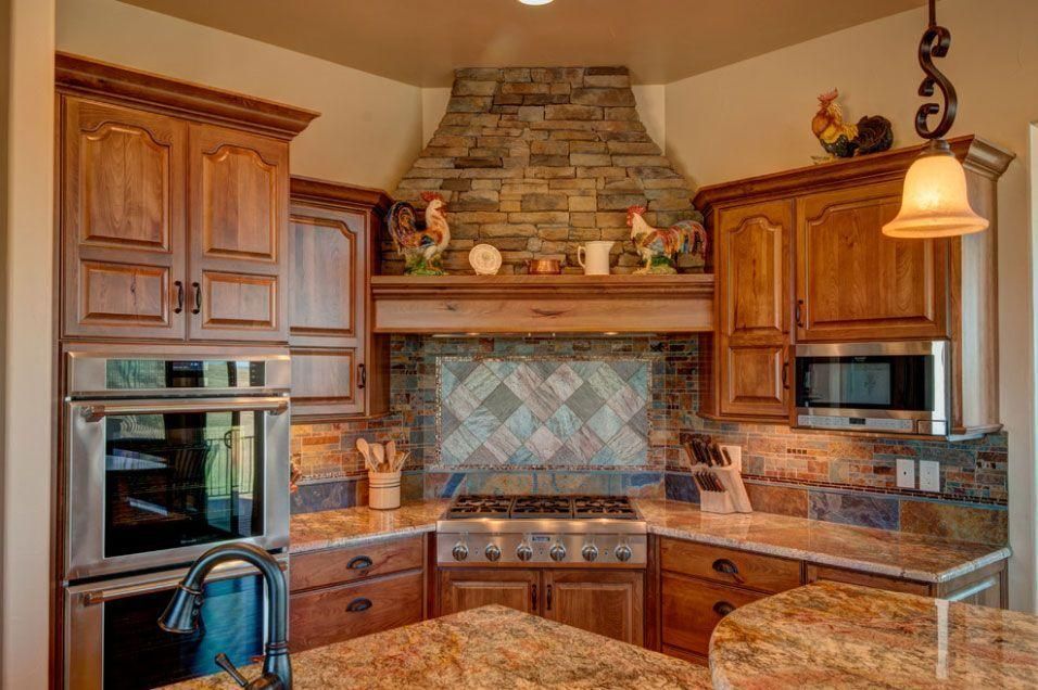 Warm-toned kitchen with granite island, wood cabinets, stainless appliances, and stone backsplash and hood