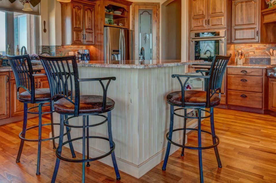 Wooden kitchen with a marble island and two tall black bar stools