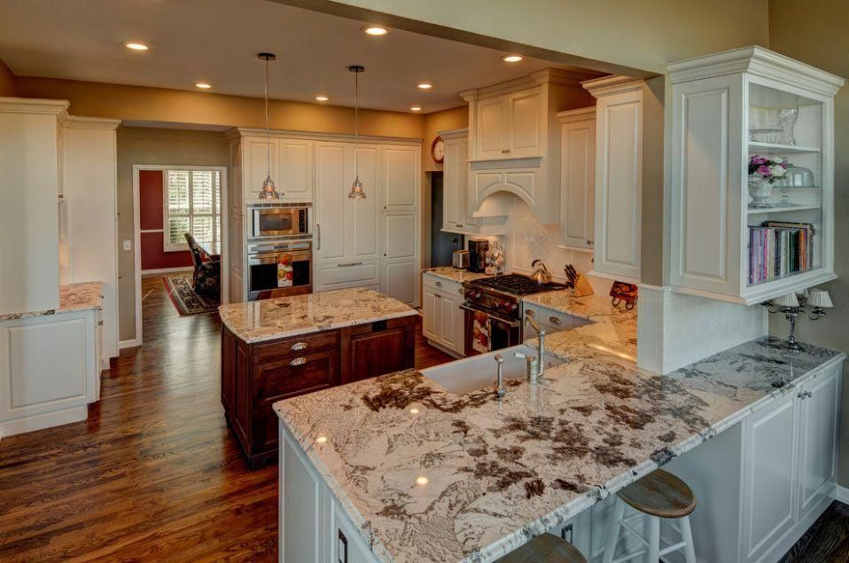 Bright modern kitchen with island, marble counters, white cabinets, and hardwood floors