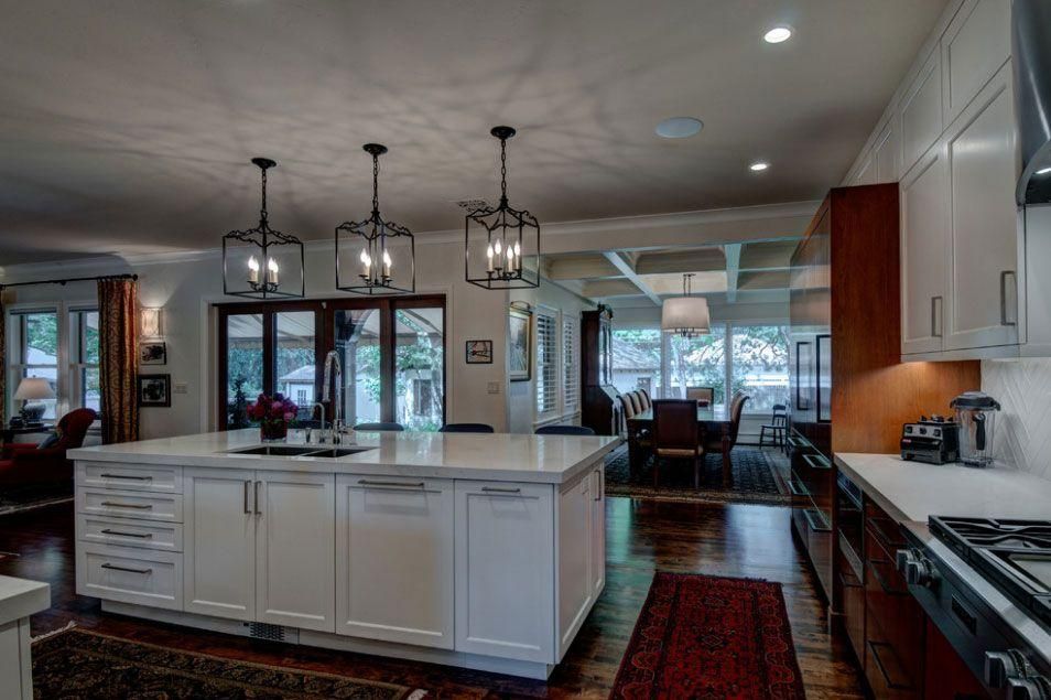 Modern kitchen with white island, pendant lights, stainless appliances, and adjoining dining area