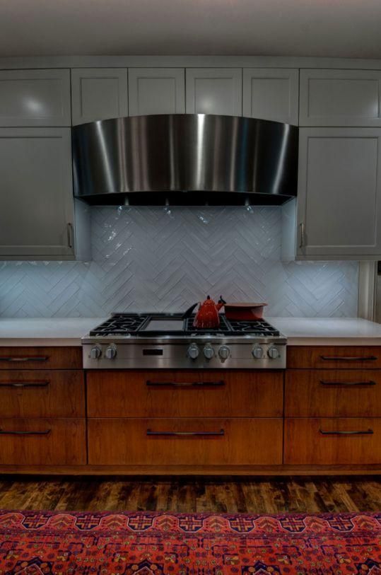 Modern kitchen with stainless range hood, gray cabinets, wood island, and patterned rug