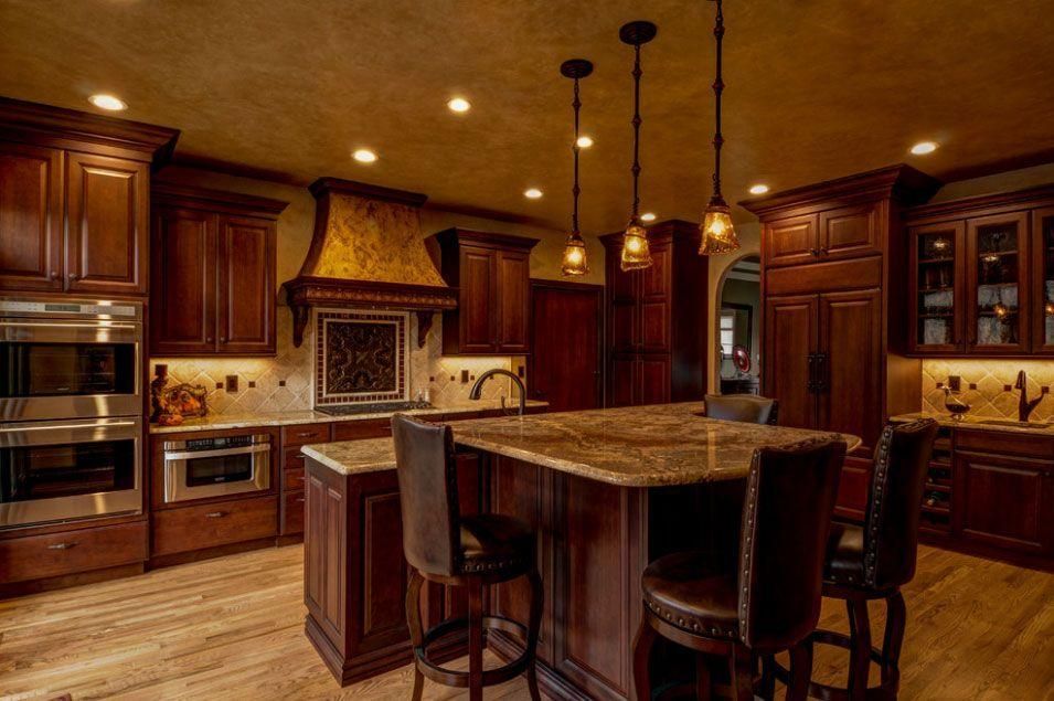 Warm-toned kitchen with dark wood cabinets, granite island, and pendant lights