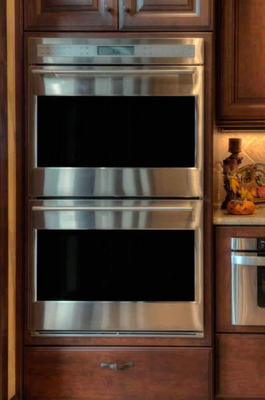Stainless steel double wall oven built into dark wood kitchen cabinets