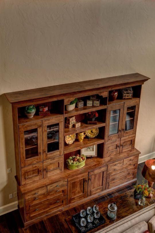 Wooden cabinet display with glass doors, shelves, and small decorative items in a home interior.