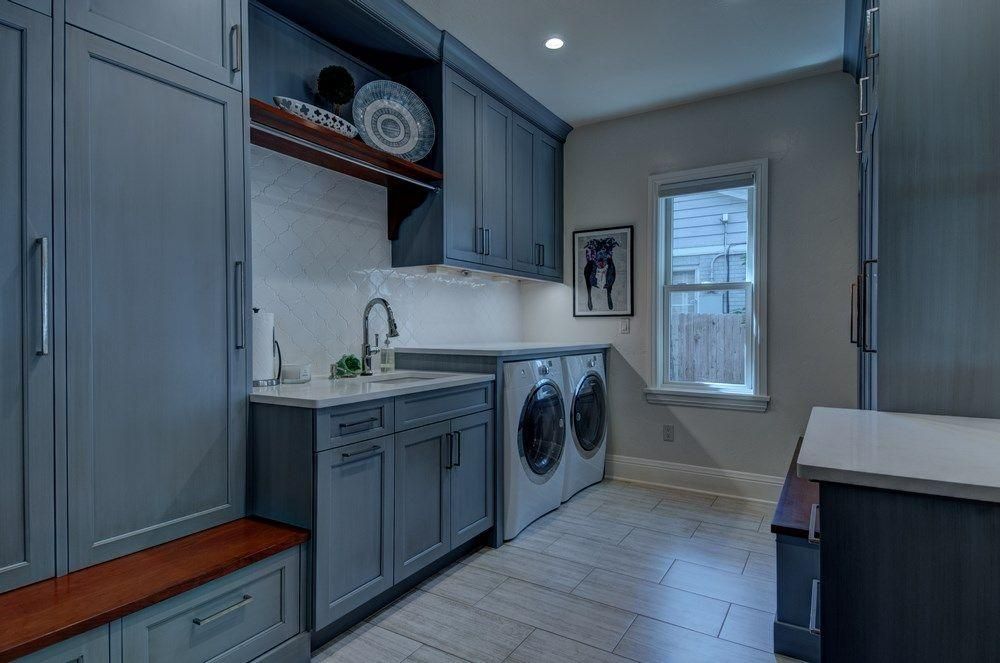 Laundry room with gray cabinets, white countertop, stacked washer-dryers, and a window.