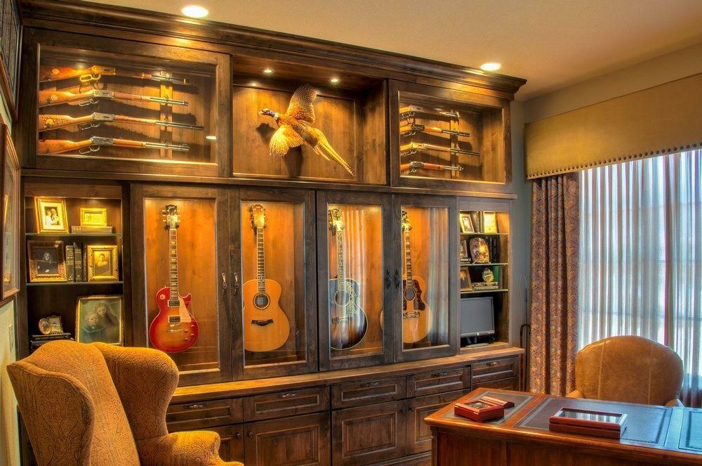 Warm wood-paneled room with guitars displayed on the wall and cozy chairs beside a small table.