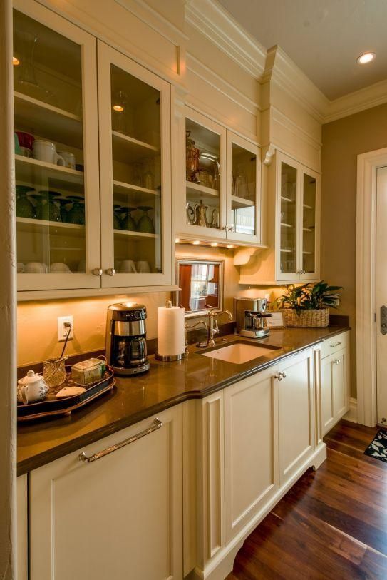Built-in kitchen buffet with glass-front cabinets, coffee station, and warm under-cabinet lighting