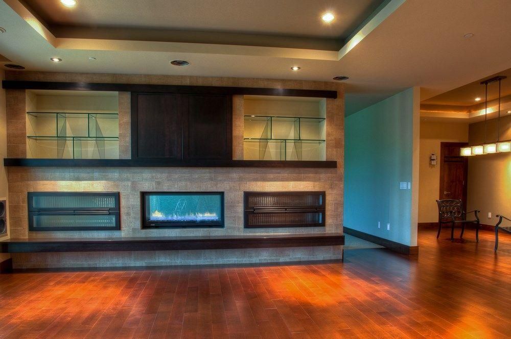 Modern living room with a built-in fireplace, dark wood accents, and polished hardwood floors.