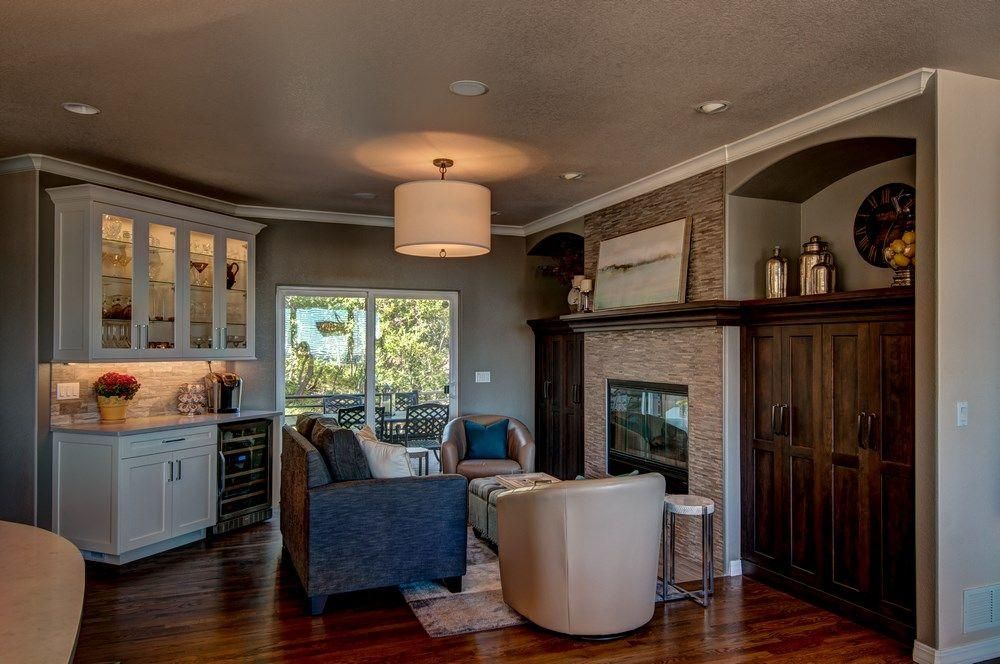 Cozy living room with fireplace, blue chairs, white cabinet, and dark wood built-in shelving