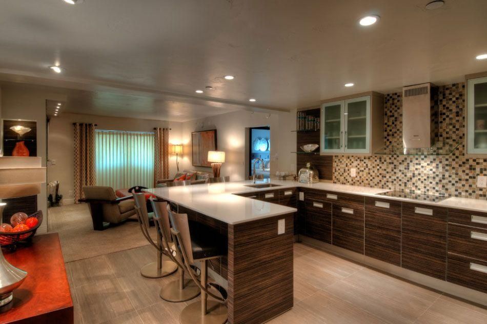 Modern kitchen with island, barstools, mosaic backsplash, and warm recessed lighting