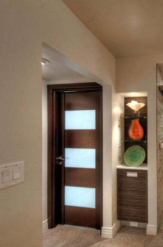Hallway with a dark wooden door, frosted glass panels, and a decorative wall niche with colored glass art.