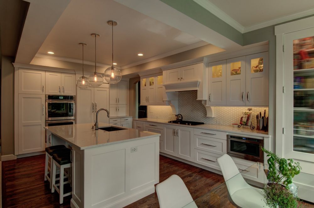 Bright white kitchen with island, pendant lights, and built-in ovens in a modern home