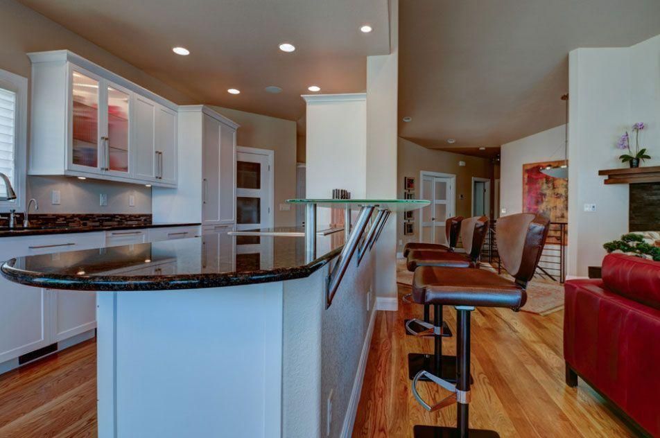 Modern kitchen with granite island opening to a hardwood living area and red sofa