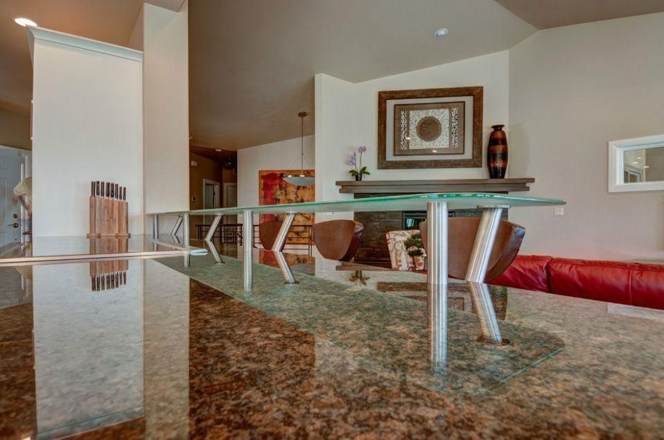Modern dining room with glass table, white chairs, marble floor, and red sofa