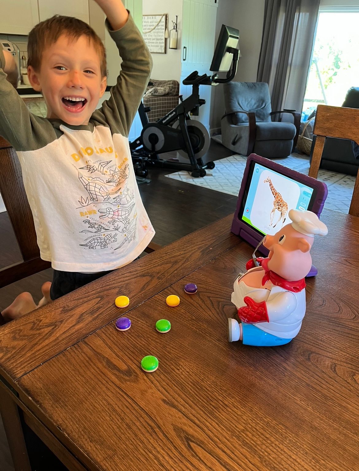 A young boy is sitting at a table playing with a toy pig.