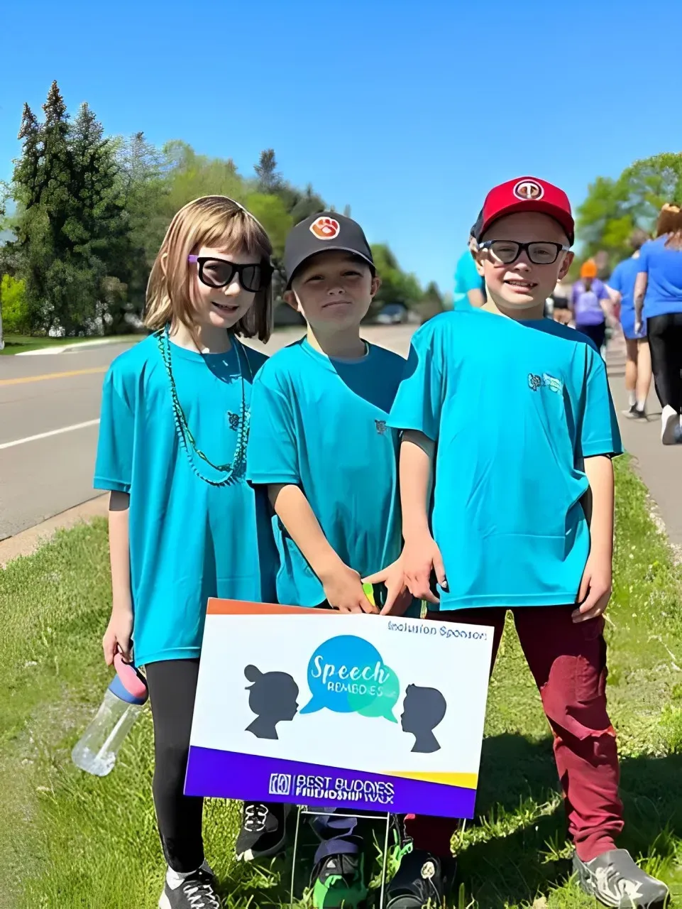Three children are standing next to each other on the side of the road holding signs.