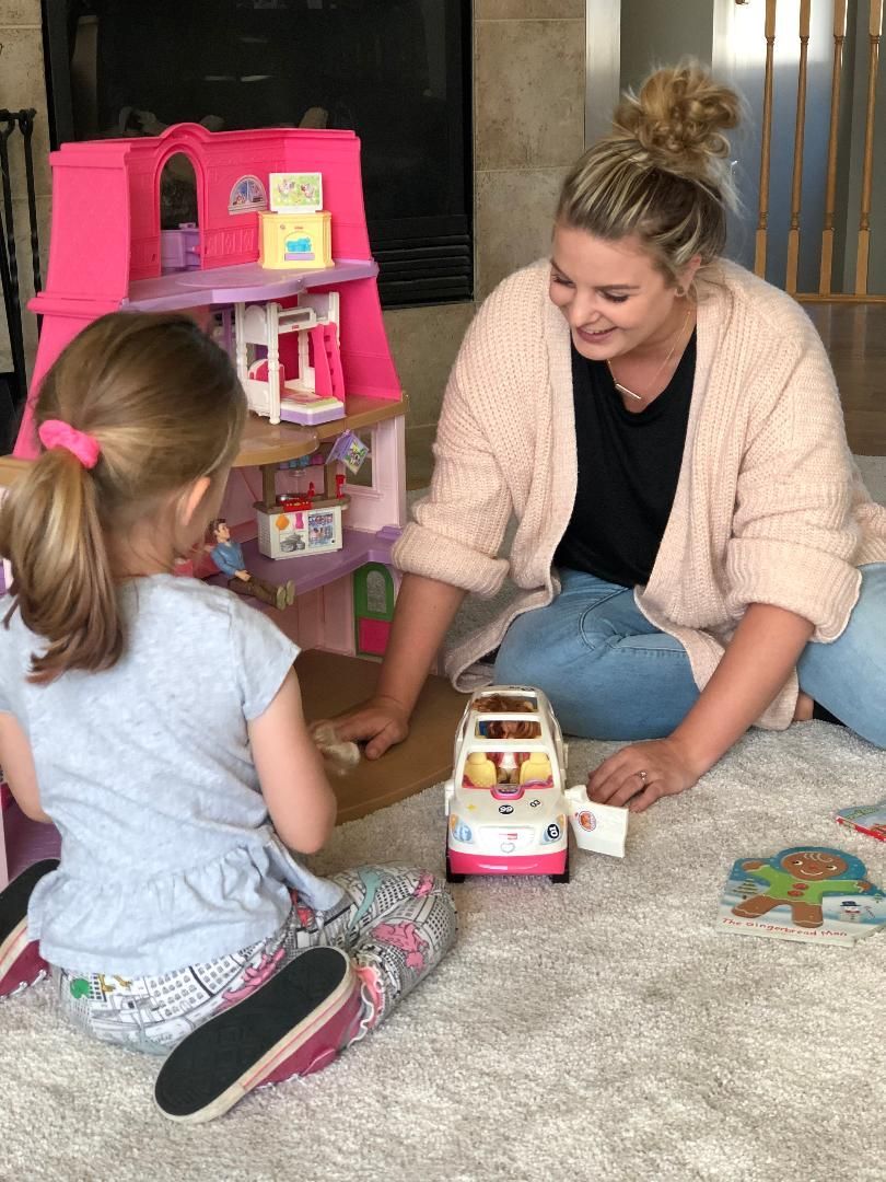 A woman and a little girl are playing with toys on the floor.