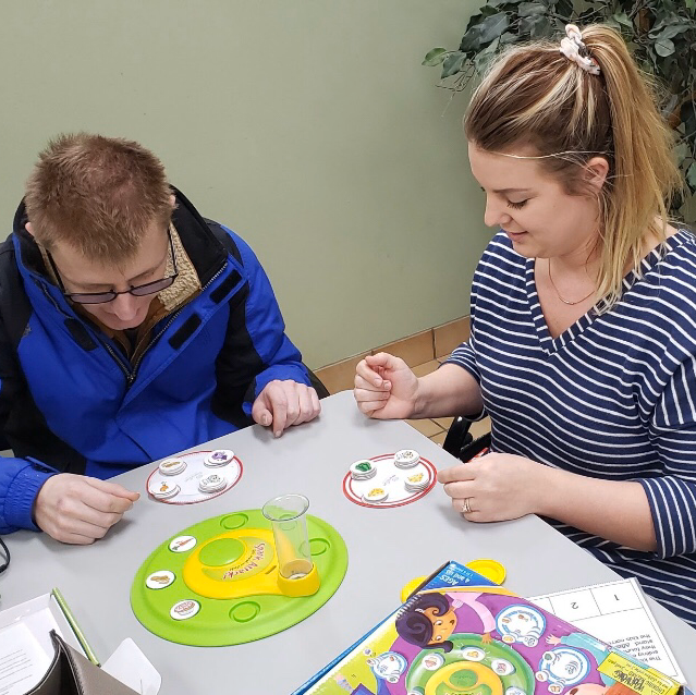 A man and a woman are sitting at a table playing a game