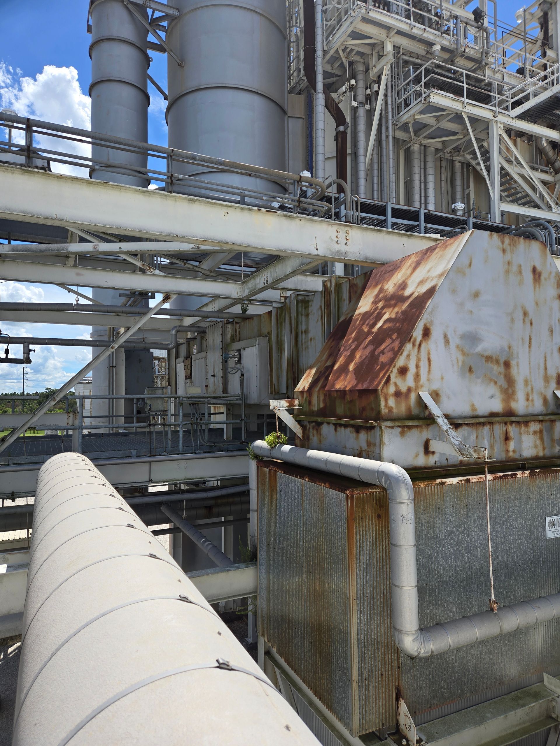 Rusty industrial machinery and piping at an outdoor factory facility